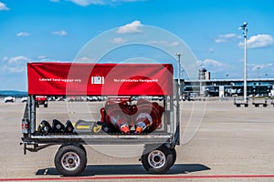 A baggage car with red cover parked on apron to serve the operation