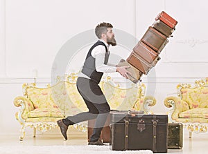 Baggage insurance concept. Porter, butler accidentally stumbled, dropping pile of vintage suitcases. Man with beard and