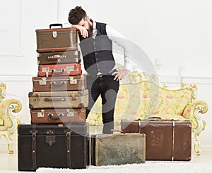 Baggage and relocation concept. Macho elegant on tired face, exhausted at end of packing, leans on pile of vintage
