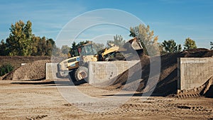 Bagger scooping gravel at construction aggregate dumps photo