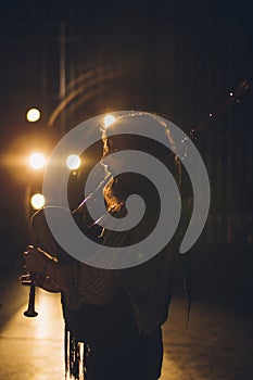 Bagpipe player playing his instrument in an auditorium with stage lights and a black background