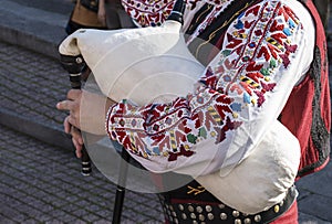 Bagpiper in traditional Bulgarian costume plays folk musical wind instrument - bagpipes at festival in Plovdiv, Bulgaria