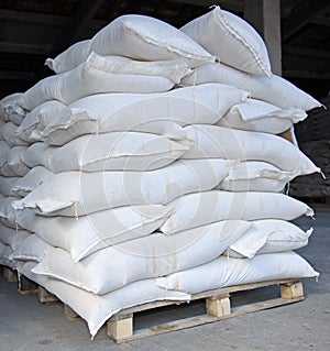 Bags of industrial cement are placed on wooden pallets.