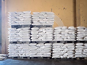 Bags of milled rice stacked on pallets and store inside a warehouse. Agricultural product processing plant. Modern rice miller.