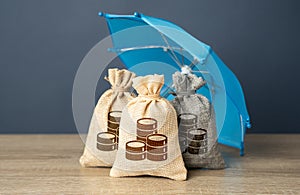 Bags of money under an umbrella. Safety of investments.