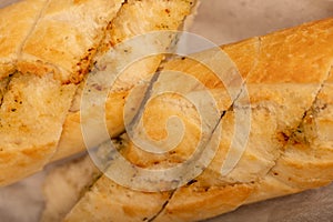 Baguette with garlic paste cut into pieces, close-up, selective focus