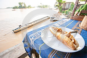 Baguette on Laotian traditional tablecloth with scenic view over the Mekong River