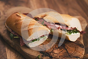 Baguette sandwiches with coppa ham on wood board