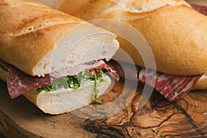 Baguette sandwiches with coppa ham on wood board