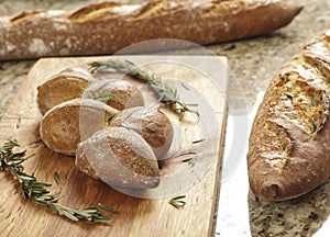 Baguettes on a counter next to a cutting board with a knife and seasonings