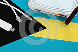 Bahamas flag depicted on table with internet rj45 cable, wireless usb wifi adapter and router. Internet connection concept