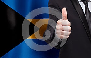 Bahamian concept. Businessman showing thumb up on the background of flag of Bahamas