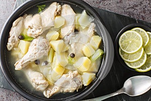 Bahamian stew with chicken wings, potatoes, celery, lime and spices in a clear broth close-up in a plate. Horizontal top view