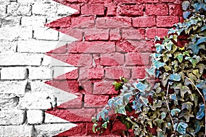 Bahrein grunge flag on brick wall with ivy plant photo