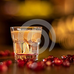 Baileys shot with grenadine seeds on wooden table