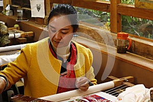 Woman working on embroidery in the village of Baisha, Lijiang, Yunnan, China