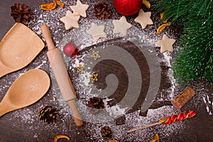 Bake pastry cookies, star-cookies, wooden kitchen utensils, shovels, rolling pin, flour scattered on a brown wooden table, pine ar