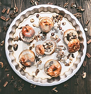 baked apples with nuts and honey a round baking tray on a wooden background, top view