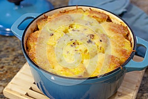 Baked Au Gratin potateos in blue cast iron baking pot with melted cheese on top