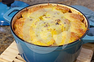 Baked Au Gratin potateos in blue cast iron baking pot with melted cheese on top