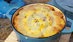 Baked Au Gratin potateos in blue cast iron baking pot with melted cheese on top