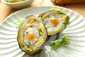 Baked avocado with eggs on plate, closeup