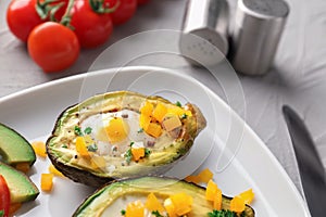 Baked avocado with eggs on plate, closeup