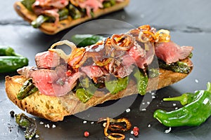 Baked baguette with pimientos and steak photo