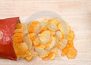 Baked BBQ potato chip bag spilling contents on a light wood table