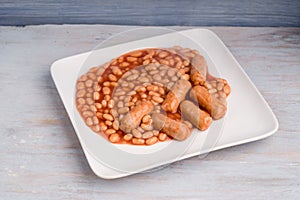 Baked beans with sausages on a wooden background