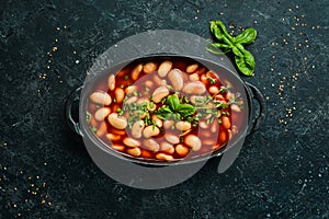 Baked beans in tomato sauce on a black stone plate.