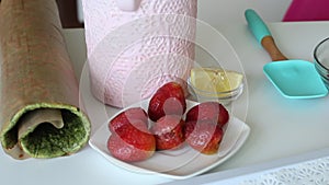 Baked biscuit cake rolled into a tube. Nearby are the ingredients for the filling. The process of making Swiss roll