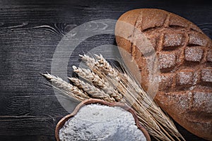 Baked bread golden wheat rye ears wooden bowl with flour on wood