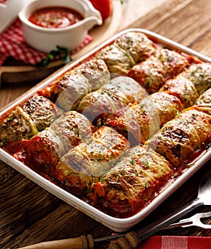 Baked cabbage rolls stuffed with groats and mushrooms in tomato sauce in a casserole dish