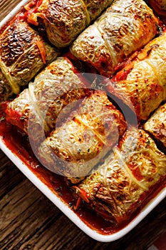 Baked cabbage rolls stuffed with groats and mushrooms in tomato sauce in a casserole dish