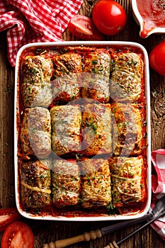 Baked cabbage rolls stuffed with groats and mushrooms in tomato sauce in a casserole dish