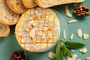 Baked camembert cheese with baguette bread grilled toasts and leaves.