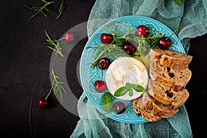 Baked Camembert cheese, toast and arugula salad with sweet cherries.