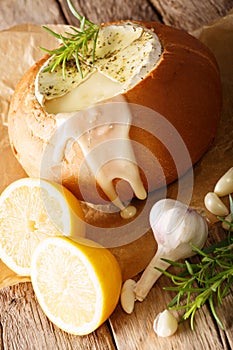 Baked Camembert with garlic and rosemary in a loaf of bread close-up. vertical