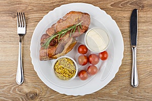 Baked carbonade, tomatoes, mustard, mayonnaise in plate, fork an