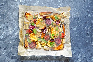 Baked carrots, beets, potatoes, zucchini and tomatoes on a baking sheet, top view food