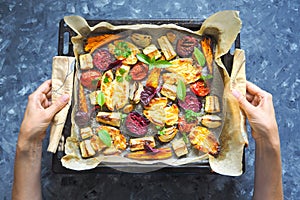 Baked carrots, beets, potatoes, zucchini and tomatoes on a baking sheet, top view food