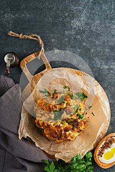 Baked cauliflower. Oven or whole baked cauliflower spices and herbs server on wooden rustic board on old gray background table. De