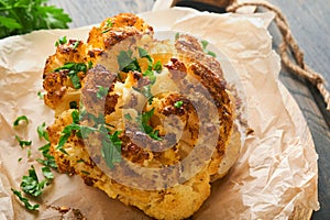 Baked cauliflower. Oven or whole baked cauliflower spices and herbs server on wooden rustic board on old wooden vintage table back