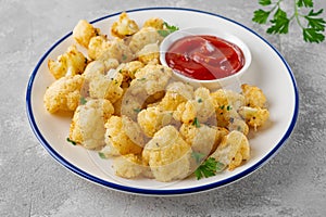 Baked cauliflower with parmesan cheese on a gray concrete background. Vegetarian healthy food