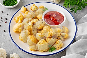 Baked cauliflower with parmesan cheese on a gray concrete background. Vegetarian healthy food