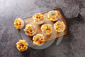 Baked Cheese and Ham Bites for Snack close-up on a wooden board. Horizontal top view