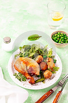 Baked chicken with baby potatoes and salad on a green background.