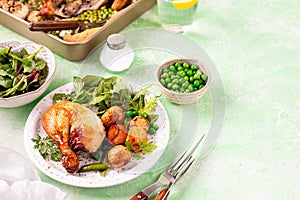 Baked chicken with baby potatoes and salad on a green background.