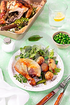 Baked chicken with baby potatoes and salad on a green background.